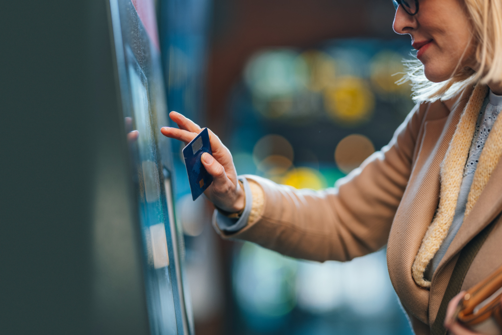 A Happy Beautiful Blonde Woman With Glasses Withdrawing Money From ATM